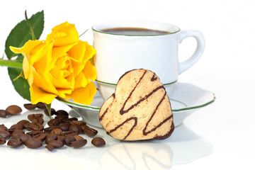 A heart shaped cookie beside a coffee cup