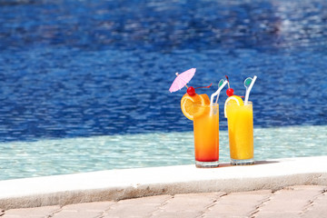 two glasses of fruit juice on blue water background