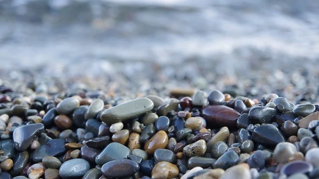Close up of very calm sea surf splashing on a pebble beach