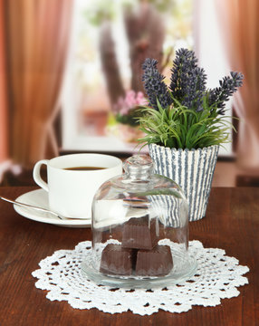 Chocolate sweets under glass cover and hot drink