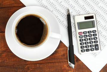 Cup of coffee on worktable covered with documents close up