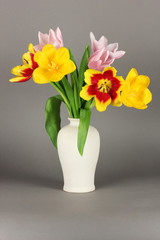 Beautiful tulips in bucket on grey background