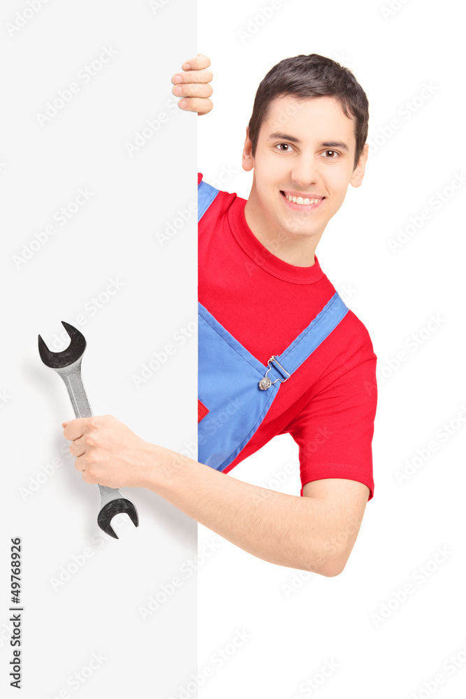 Wall mural Repairman holding a wrench and posing behind a blank panel