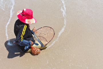 A thai fisherman is searching for shells (Pharella javanica) on
