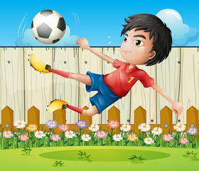 Un garçon jouant au football à l& 39 intérieur de la clôture