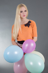 attractive woman holding balloons over grey