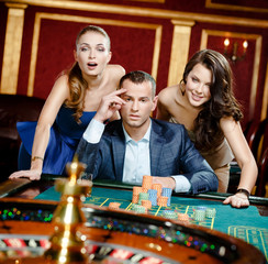 Man with two women playing roulette at the casino