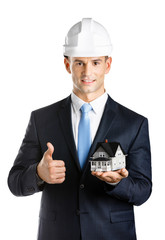 Engineer in white hard hat shows small model house