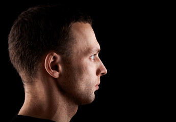Profile portrait of young man isolated on black