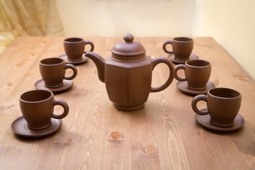 Clay teapot and cups on a wooden table