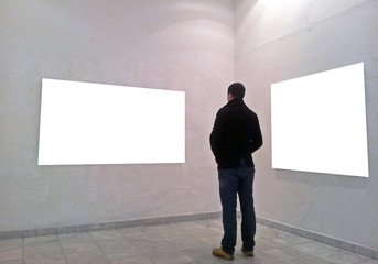 Man in gallery room looking at empty frames