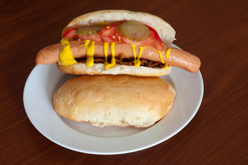 Hot dog roll with pickled cucumber, mustard and tomato sauce