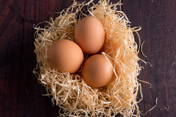 Easter eggs in the basket of hay on a wooden