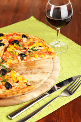 Tasty pizza with wine on wooden table close-up