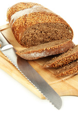 Bread with sesame seeds and knife on wooden board close up