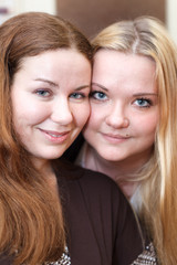 Two joyful Caucasian young women together looking at camera