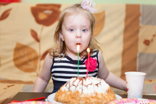 Little Caucasian girl two ears blowing candles on birthday cake