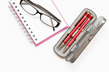 pink notebook with two red pen and eyegless white background