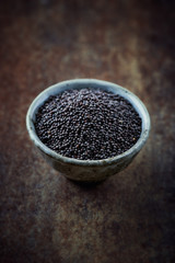 Black mustard seeds in a small ceramic bowl