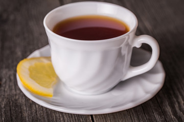 Hot cup of tea in white mug with lemon. Standing on wooden table