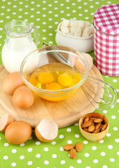 Broken egg in bowl and various ingredients next to them