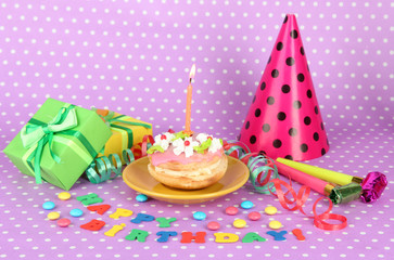 Colorful birthday cake with candle and gifts on pink background