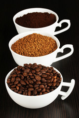 Different types of coffee in three cups on wooden table