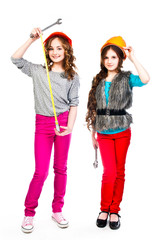 Two young beautiful girls in building helmet and tools in hand