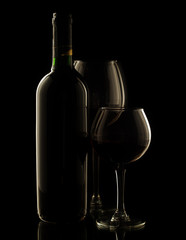 Red wine bottle and glass on dark background