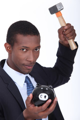Man about to break open a piggy bank with a hammer