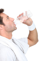 Man in gym clothes drinking a bottle of water