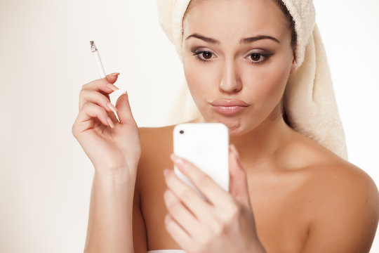 girl with a cigarette and looking at herself in her smartphone
