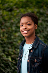 An African-American girl in front of an ivy wall.