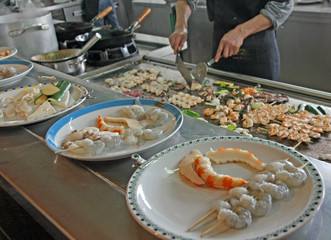 chef prepares dishes with vegetables and meat cooked on a griddl
