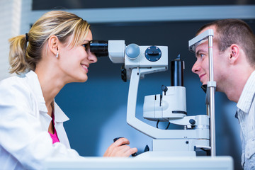 Optometry concept - handsome young man having his eyes examined