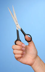 Female hand with scissors on color background