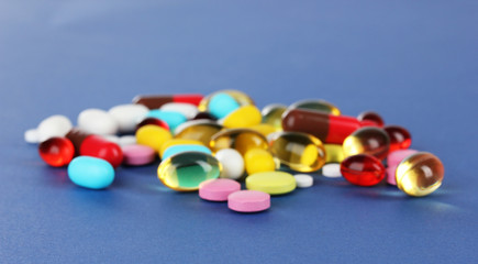 Assortment of pills, tablets and capsules on blue background