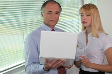 Businessman looking at a laptop with his assistant