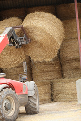 Obraz premium Tractor lifting bail of hay