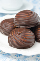 Marshmallows in chocolate on a white plate, closeup