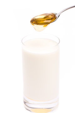 Honigmilch: Glas, Milch, Löffel und Honig auf weißem Hintergru