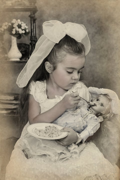 Little girl is feeding her doll