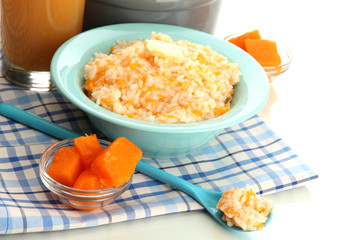 Rice porridge with pumpkin in blue bowl and glass of juice,