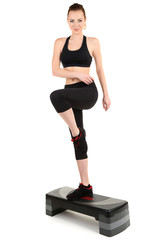 Young woman doing fitness exercises on stepper isolated on