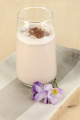 Glass of chocolate-cream cocktail on wooden table close-up