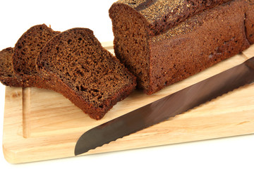 Sliced black bread and knife on wooden board close up