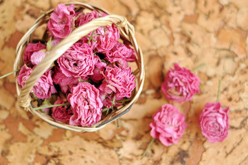 Small pick roses in a handmade straw basket on a wooden table