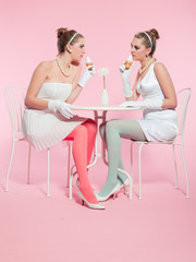 Two girls blonde hair fifties fashion style eating ice cream.