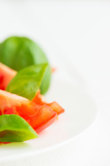 Fresh tomatoes with basil leaves in a plate