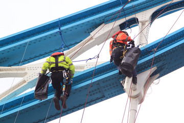 Workers hanging from bridge